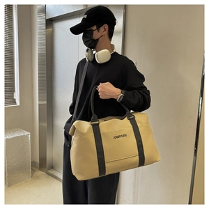 Detail of khaki fitness travel bag with black straps worn by model in elevator setting