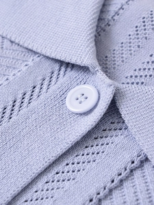 Detail of light blue knit polo top with diamond cut-out texture and four-hole buttons