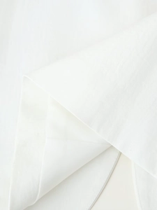 Detailed macro view of high-quality white embroidered fabric texture on fashion jacket