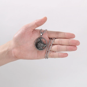 Detailed shot of a silver viking wolf head pendant on a twisted chain held in hand