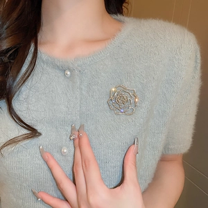 Detailed view of hollow rose brooch with crystals on a blue mohair cardigan