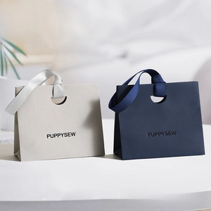 Close-up of textured paper gift bags with silk ribbon handles and PUPPYSEW logo