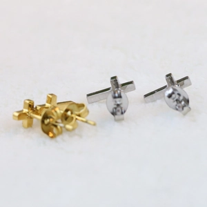 Close-up of gold and silver cross stud earrings with butterfly backs on white fur