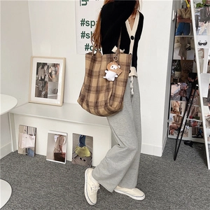 Close-up of a large checkered wool tote bag with a cute white plush bear pendant detail