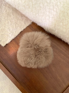Détail de la pince à cheveux en peluche marron douce sur fond en bois rustique
