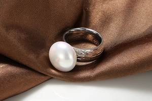 Macro view of wide hammer-textured stainless steel ring with a large white pearl