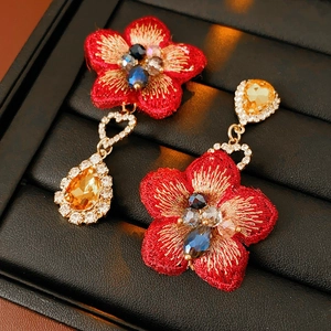 Détail macro de boucles d'oreilles vintage avec fleurs en tissu rouge et cristal goutte ambre