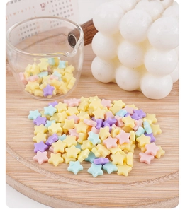 Gros plan de perles de cire en forme d'étoile aux couleurs macaron sur un plateau en bois
