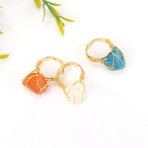 Detail of three handmade gold wire wrapped natural agate rings in orange and blue colors