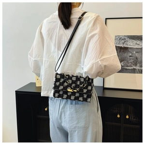 Sac à bandoulière en toile à carreaux porté par un mannequin avec détail de chaîne en métal