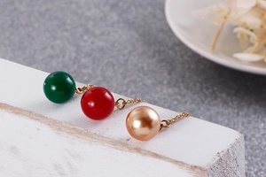 Détail de pendentifs en perles rouge vert et champagne sur chaînes dorées