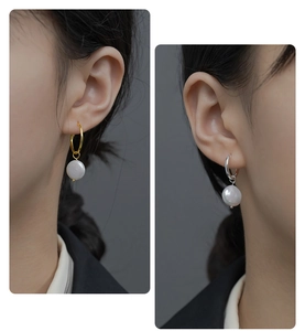 Close-up of elegant gold and silver hoop earrings with white round pearls on a model