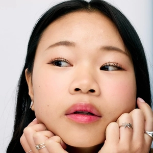 Close-up of a female model wearing a silver bow ring and minimalist bands