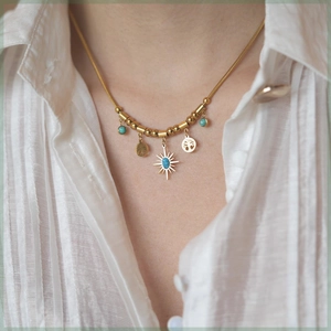Detail of tree of life and turquoise pendants on a gold snake chain worn by a model