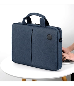 Detail of blue canvas laptop bag on a table showing handle and texture in office setting