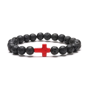 Macro detail of natural black lava stone beads with a red cross accent bracelet