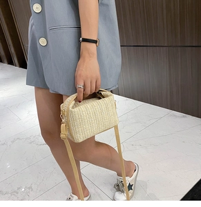 Close-up of woven straw texture and adjustable leather strap on a beige summer crossbody bag