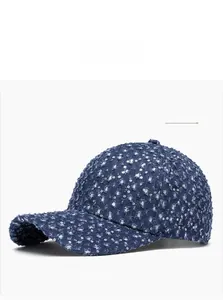 Detailed close-up of blue denim baseball cap featuring silver sequins and distressed rips