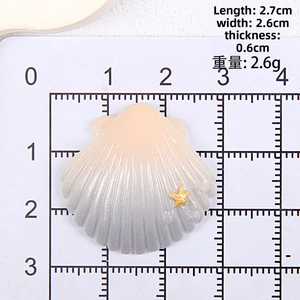 Top view of shell DIY resin charm with starfish detail on ruler for size reference