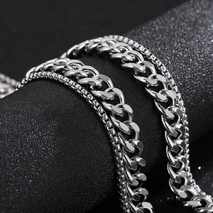 Detail of silver stainless steel cuban and box chains wrapped on a matte black cylinder