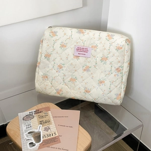 Macro detail of quilted cream floral cosmetic bag with soft cotton texture and zipper
