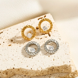 Detailed view of gold and silver twisted rope earrings with cubic zirconia on stone