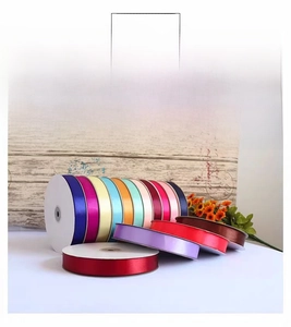 Close-up of colorful satin ribbons with gold metallic edges on white plastic spools