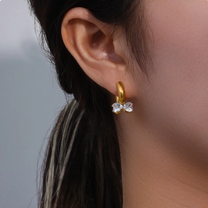 Minimalist gold bow-shaped hoop earrings featuring two heart-shaped clear zircons for women