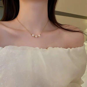 Close-up of elegant gold fishtail necklace with white pearls on a model neck