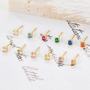 Detailed set of twelve colorful zircon silver stud earrings on decorative white paper