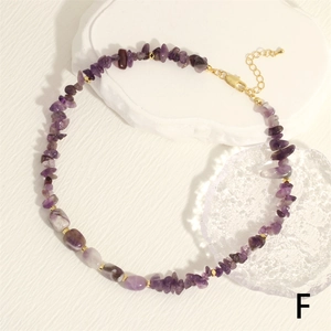 Close-up of irregular purple stone necklace with gold beads and lobster clasp on stone