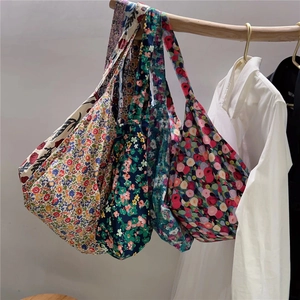 Detail view of four floral pattern cotton tote bags hanging on a wooden hanger