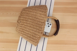 Top-down view of woven straw handbag interior showing spacious capacity with a smartphone