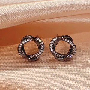 Macro view of black twisted hoop earrings with shimmering cubic zirconia on satin fabric