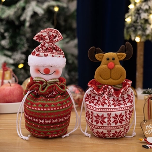 Close-up of knit Christmas apple gift bags with snowman and reindeer on wooden table