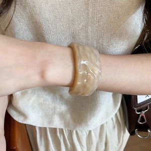 Macro detail of cream resin cuff bracelet with marble texture and wavy pattern