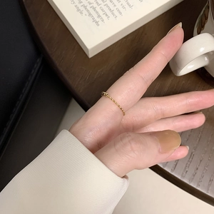 Gros plan d'une bague fine dorée hexagonale portée par un mannequin dans une ambiance douce