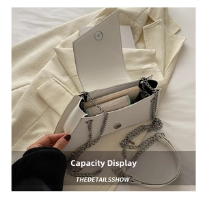 Internal view of white envelope chain bag showing storage space for phone and card holder