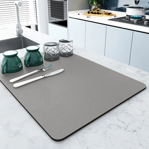 Grey rectangular absorbent kitchen drying mat on white marble countertop with modern decor