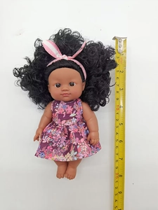 Detail view of 9-inch black curly hair doll in floral dress with measuring tape for scale