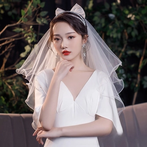 Detail of white double-layer bridal veil with bow hairpiece and soft mesh texture