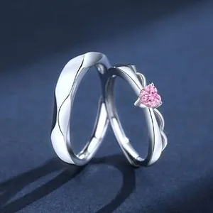 Close-up of S925 silver couple rings featuring a pink heart zircon and wavy textures