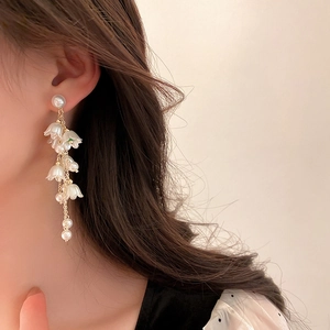 Eleganti orecchini a mughetto con perle e catena d'oro indossati da una modella