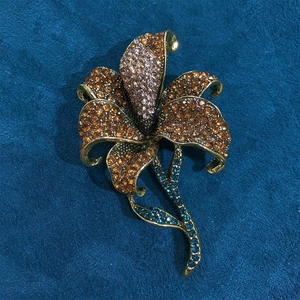 Detail of vintage lily flower brooch with amber and pink rhinestones on bronze base