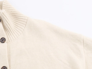 Détail du cardigan en maille beige avec col roulé côtelé et boutons en écaille
