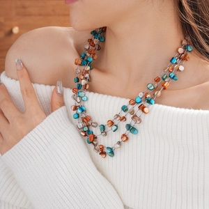 Detail of multilayer shell bead necklace in turquoise and brown on a model
