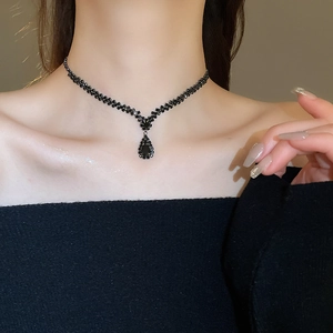 Close-up of elegant black waterdrop pendant necklace with sparkling pavé diamonds on model