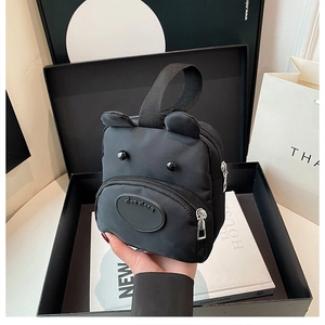 Detailed macro view of a cute black bear cartoon handbag with ears and smooth nylon texture