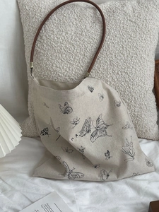 Detail of butterfly print canvas bag with brown leather strap on soft textures