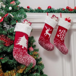 Drei rote Strick-Weihnachtssocken mit Elch- und Baummustern auf einem Kaminsims